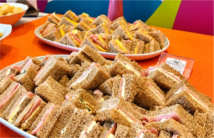 Mini sanduíches de pão integral com frios e queijo preparados pela Mamanduca para buffet de inauguração de empresa e eventos corporativos.